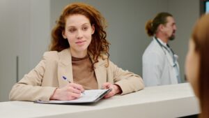 Recepcionista atendiendo con amabilidad, reflejando una experiencia del paciente en una clínica médica.